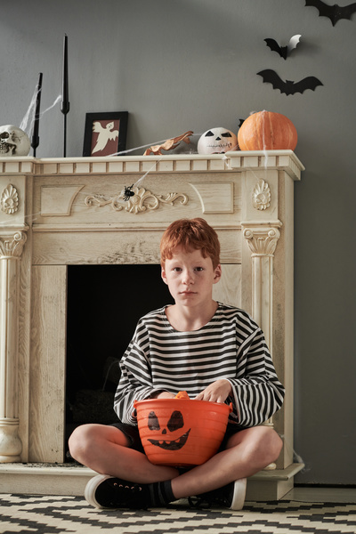 Boy Sits with Bucket with Halloween Treats